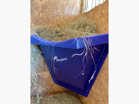 Blue Hay Feeder attached to wall inside stables.