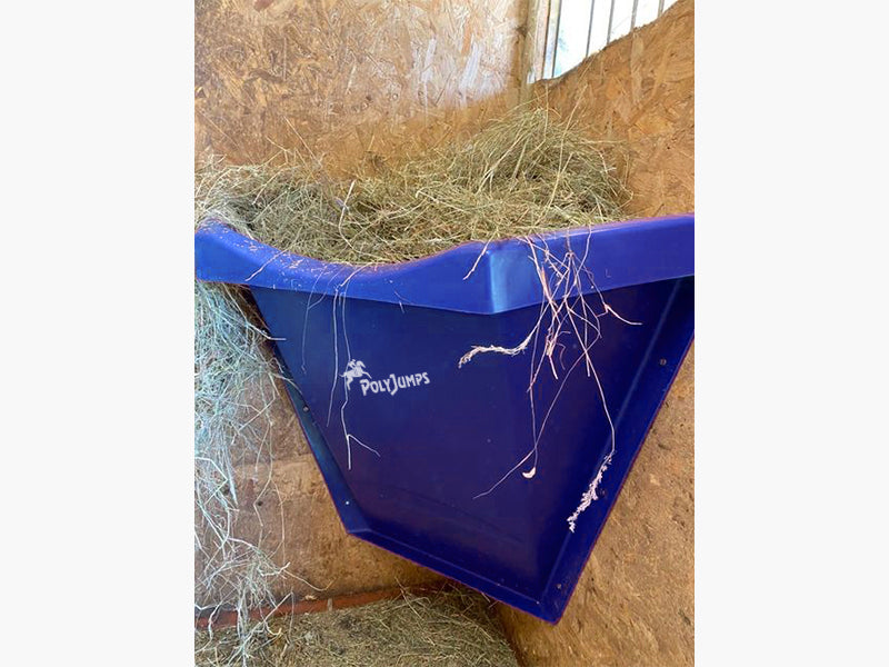 Blue Hay Feeder attached to wall inside stables. 