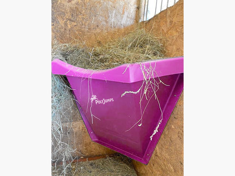 Pink Hay Feeder attached to wall inside stables.