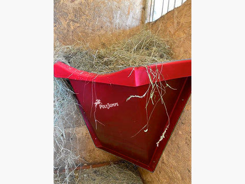 Red Hay Feeder attached to wall inside stables.