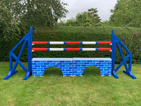 Photograph of a pair of Blue Cross Wings with 2 9 Band Practice Poles coloured: Red, Blue & White. Underneath the poles sit 2 White Bridge Fillers with Blue Brick Graphics on them.