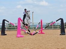 Load image into Gallery viewer, Horse and rider jumping over the middle of the PolyJumps Spider Set; comprised of 2 pairs of 8 Cups, one Black the other Pink with 4 9 Band Pro Poles. Alternate colouring: Pink, White &amp; Black and, Black, White &amp; Pink. 
