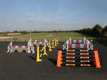 Load image into Gallery viewer, Photograph of the PolyJumps Advanced set in an arena. The set&#39;s contents are as follows: 1 set of Combi Blocks, 4 sets of Cross Wings and 3 sets of 8 Cups with 4 Bridge Fillers and 21 Poles. This set&#39;s colour scheme is varied, from Orange to Yellow to White.
