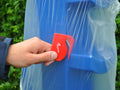 Red BaleBuster being used to cut open the plastic wrap on a Blue 8 Cup.
