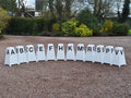 12 Dressage Tower Markers sat on gravel. Black painted letters on all sides (A, B, C, E, F, H, K, M, R, S, P, V).