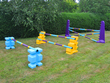 Load image into Gallery viewer, Photograph of the Club Jump Set. From left to right, 1 pair of Baby Blue PolyJump Block holding 1 9 Band Practice Pole: Club Style. 1 pair of Yellow MultiJumps holding 2 9 Band Practice Poles: Club Style. 1 pair of Purple 8 Cups holding 3 9 Band Practice Poles: Club Style.  
