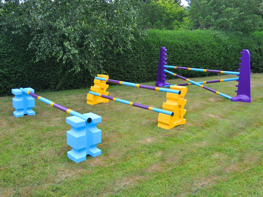 Photograph of the Club Jump Set. From left to right, 1 pair of Baby Blue PolyJump Block holding 1 9 Band Practice Pole: Club Style. 1 pair of Yellow MultiJumps holding 2 9 Band Practice Poles: Club Style. 1 pair of Purple 8 Cups holding 3 9 Band Practice Poles: Club Style.  