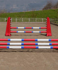 A pair of Red Hedgehogs with 3 Pro Poles 9 Band coloured: Red, Blue & White. Behind them is a pair of Red 8 Cups with 2 poles in an arena.