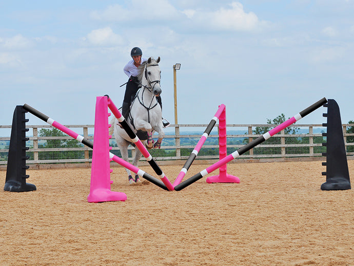 Horse and rider jumping over the middle of the PolyJumps Spider Set; comprised of 2 pairs of 8 Cups, one Black the other Pink with 4 9 Band Pro Poles. Alternate colouring: Pink, White & Black and, Black, White & Pink. 