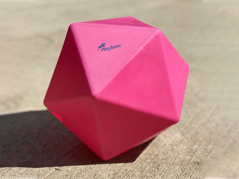 Pink Treat Ball on floor with blue PolyJumps logo facing upward.