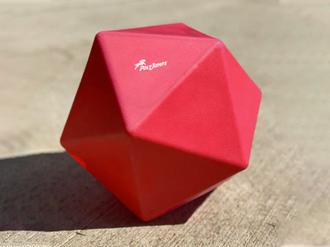 Red Treat Ball on floor with white PolyJumps logo facing upward.